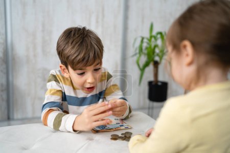 Photo for Siblings boy and girl small caucasian child brother and sister play at home with piggy bank saving money childhood investment insurance and finance concept copy space - Royalty Free Image