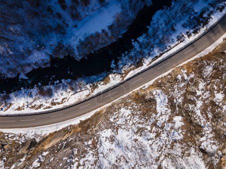 Téléchargez les photos : Aerial drone view on the road trough the hill and mountain in winter day covered with snow with rock and trees and river in Serbia - en image libre de droit