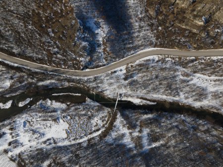 Photo for Aerial drone view on the road trough the hill and mountain in winter day covered with snow with rock and trees and river in Serbia - Royalty Free Image