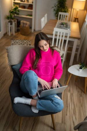 Téléchargez les photos : One young woman use laptop computer at home while sit comfortable - en image libre de droit