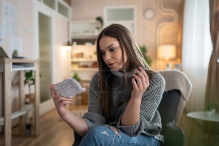Foto de Una mujer joven caucásica hembra sentarse en casa humo cigarrillo leer nota - Imagen libre de derechos
