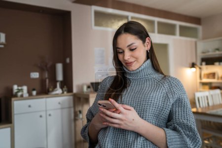 Foto de One woman caucasian young female sitting at home use mobile smartphone to browse internet browse social network or for sms message read or send real people copy space - Imagen libre de derechos