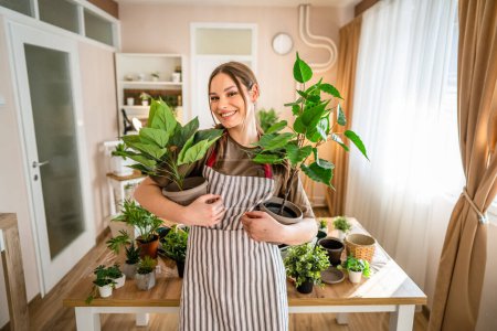 Foto de One woman young caucasian female stand at home hold flower plants pot happy smile waist up front view gardening and botany horticulture care concept copy space - Imagen libre de derechos