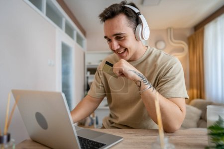 Ein Mann erwachsenen kaukasischen männlichen sitzen zu Hause glücklich Lächeln am Laptop Computer halten Bank Kreditkarte Online-Shopping-Konzept echte Menschen kopieren Raum E-Commerce