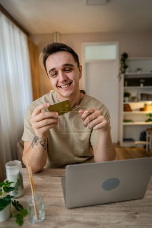 Foto de Un hombre adulto caucásico macho sentarse en casa feliz sonrisa en el ordenador portátil celebrar banco tarjeta de crédito en línea concepto de compras personas reales copiar espacio e-commerce - Imagen libre de derechos