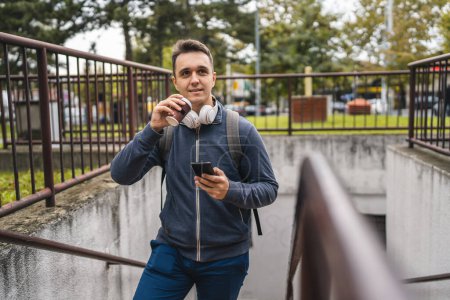 Photo for One man young adult male walking up the stairs steps in the city in day with cup of coffee and mobile phone real people tourist or student copy space talking on smartphone - Royalty Free Image