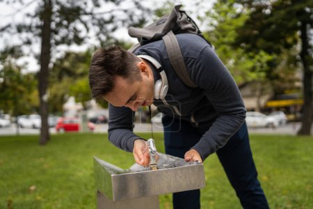 Téléchargez les photos : One man caucasian male drink water at public fountain in the city town - en image libre de droit