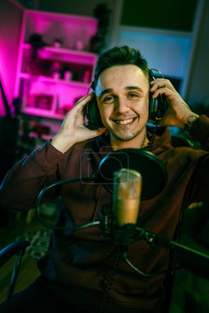 Foto de One man caucasian male blogger or vlogger gesticulating while streaming video podcast in broadcasting studio use microphone and headphones famous influencer shooting video for channel podcast - Imagen libre de derechos