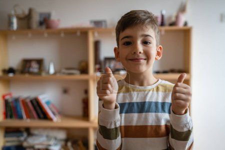 Téléchargez les photos : Portrait d'un garçon caucasien préscolaire enfant à la maison tour de taille pouces vers le haut heureux succès - en image libre de droit