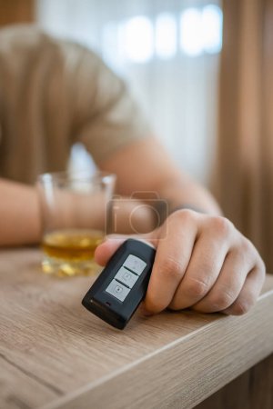Téléchargez les photos : Un homme assis à la maison avec une bouteille d'alcool boire du whisky alcoolique abus d'alcool, addiction et l'homme dépression concept boire et conduire copie espace tenir les clés de voiture près de la main - en image libre de droit