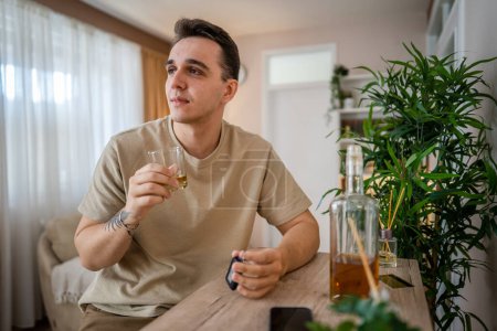 Foto de One man sit at home with bottle of liquor drink whiskey drunk alcoholic Alcohol abuse, addiction and man depression concept drink and drive copy space hold car keys - Imagen libre de derechos
