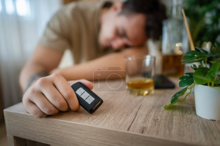 Photo for One man sit at home with bottle of liquor drink whiskey drunk alcoholic Alcohol abuse, addiction and man depression concept drink and drive copy space hold car keys - Royalty Free Image