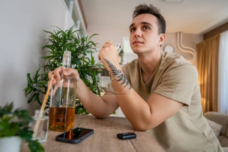 Foto de One man sit at home with bottle of liquor drink whiskey drunk alcoholic Alcohol abuse, addiction and man depression concept copy space - Imagen libre de derechos