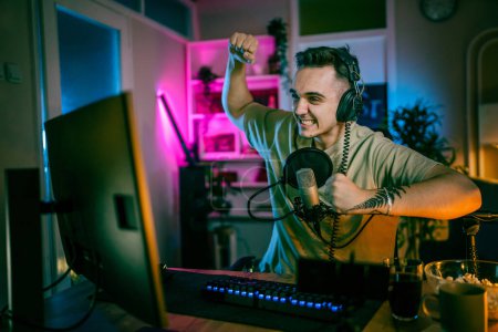 Photo for Young man play video games on pc computer while streaming to social media or internet online video male gamer at home wear headphone frustrated losing copy space - Royalty Free Image