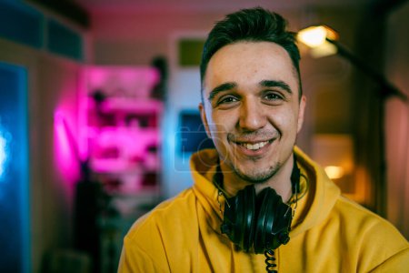 Selbstporträt eines Mannes kaukasischen männlichen Streamer Blogger oder Content Creator mit Kopfhörern auf dem Kopf glückliches Lächeln zuversichtlich in seinem Studio Kopierraum Benutzer generierte Inhalte UGC