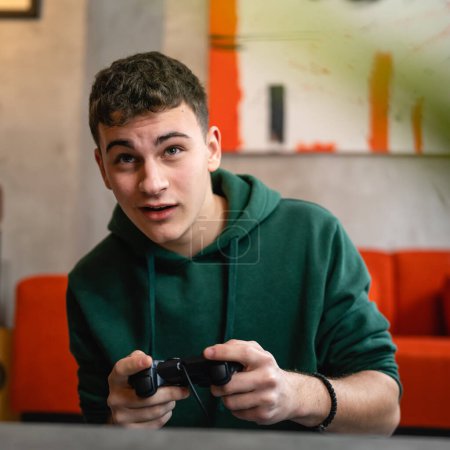 Téléchargez les photos : Un adolescent caucasien mâle jeune homme jouer console jeu vidéo à la maison - en image libre de droit