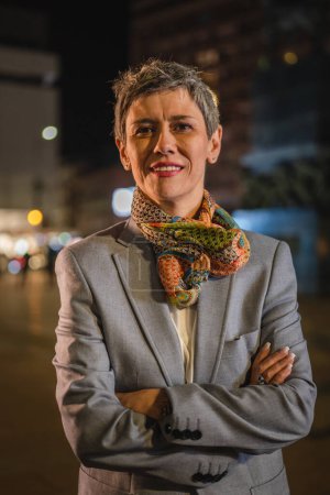Photo for Portrait of one senior woman modern mature caucasian female with gray short hair stand in the city at night real person copy space waist up - Royalty Free Image