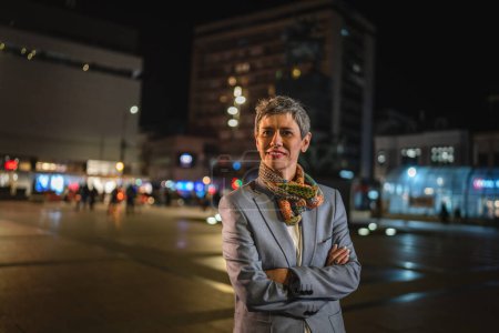 Téléchargez les photos : Portrait d'une femme âgée femme caucasienne mature moderne avec des cheveux courts gris stand dans la ville la nuit espace de copie personne réelle tour de taille - en image libre de droit