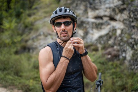 Téléchargez les photos : Un homme caucasien adulte faire du vélo électrique e-bike dans la journée ensoleillée d'été se préparer devant la maison porter un casque de protection et des lunettes les vraies personnes copier l'espace - en image libre de droit