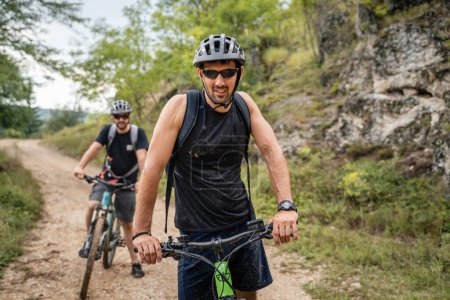 Téléchargez les photos : Homme caucasien mâle cycliste équitation e-bike vélo électrique en plein air dans la chaîne de montagnes à la gorge ou la crête porter un casque de protection et des lunettes dans l'espace de copie de jour ensoleillé - en image libre de droit