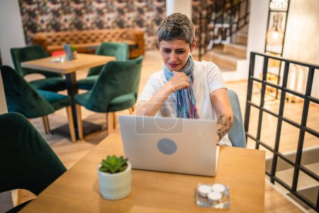 Téléchargez les photos : Une femme adulte mature caucasienne senior femme assise à la table café travaillant sur ordinateur portable à distance en ligne de vraies personnes copier l'espace moderne concept de style de vie confiant femme entrepreneur - en image libre de droit