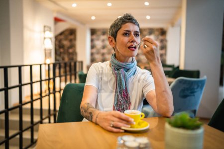 Photo for One woman senior caucasian female sit at cafe or restaurant have a cup of coffee real people copy space modern gray short hair person sitting alone - Royalty Free Image
