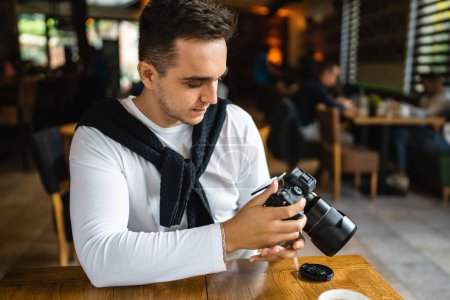 Photo for One man use digital mirrorless camera while sit at cafe or restaurant caucasian young adult photographer taking a brake at work real person copy space - Royalty Free Image