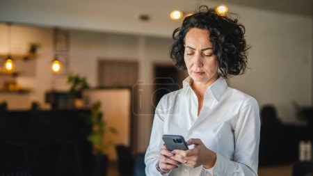 Foto de Una mujer madura usa el teléfono inteligente en casa o en el trabajo frustrado loco - Imagen libre de derechos