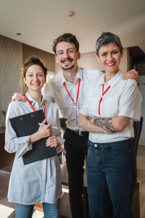Photo for Front view portrait of group of people prepare for business conference man and women three people stand happy smile in hotel room posing to camera happy smile wear white shirts real people copy space - Royalty Free Image