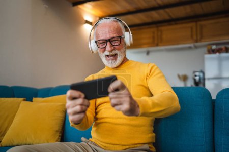 Photo for One senior old caucasian man sit at home happy smile play video games leisure activity having fun hold mobile phone smartphone have fun copy space - Royalty Free Image