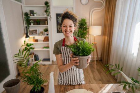 Téléchargez les photos : Une jeune femme caucasienne jardinière ou fleuriste portrait prendre soin et cultiver des plantes de fleurs domestiques à la maison jardinage concept copier l'espace - en image libre de droit