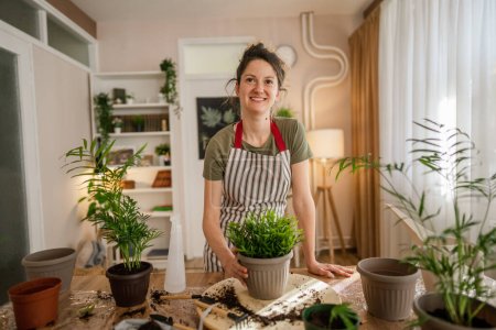Téléchargez les photos : Une jeune femme caucasienne jardinière ou fleuriste portrait prendre soin et cultiver des plantes de fleurs domestiques à la maison jardinage concept copier l'espace - en image libre de droit