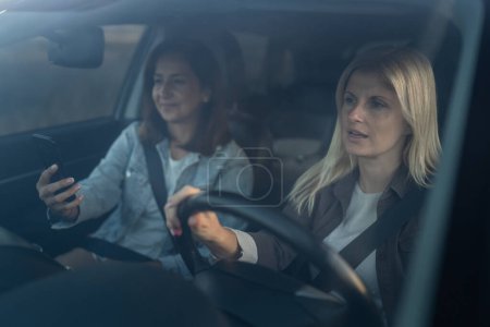 Téléchargez les photos : Deux femmes conduisent dans une voiture Voyage mature caucasienne amies sur la route dans l'automobile personnes réelles copier l'espace - en image libre de droit
