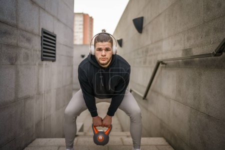One man young caucasian male athlete stand outdoor in day training with russian bell girya kettlebell weight exercise real person copy space