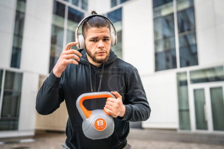 One man young caucasian male athlete stand outdoor in day posing with russian bell girya kettlebell weight real person copy space