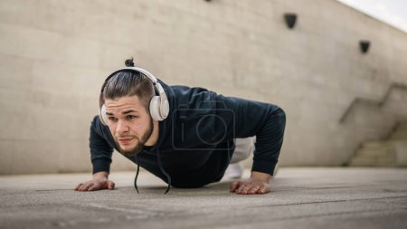 Foto de Un hombre joven adulto caucásico masculino entrenamiento al aire libre haciendo flexiones - Imagen libre de derechos
