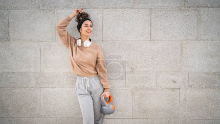 Foto de Una mujer joven atleta caucásica pie al aire libre en el entrenamiento de día con campana rusa girya kettlebell peso ejercicio persona real copiar espacio - Imagen libre de derechos