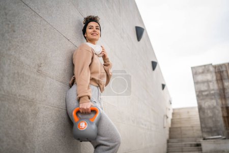 Photo for One woman young caucasian female athlete stand outdoor in day training with russian bell girya kettlebell weight exercise real person copy space - Royalty Free Image