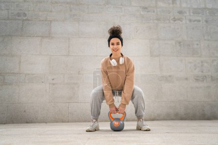 Photo for One woman young caucasian female athlete stand outdoor in day training with russian bell girya kettlebell weight exercise real person copy space - Royalty Free Image