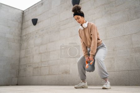 Foto de Una mujer joven atleta caucásica pie al aire libre en el entrenamiento de día con campana rusa girya kettlebell peso ejercicio persona real copiar espacio - Imagen libre de derechos