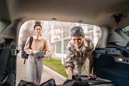 Téléchargez les photos : Deux belles femmes étudiantes mère et fille concept de voyage féminin prendre bagages valise et autres effets personnels de l'arrière de la voiture tout en déménageant dans un dortoir sur le campus de l'université ou Voyage - en image libre de droit