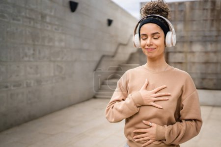 Foto de Una mujer adulta caucásica hembra usando auriculares para la meditación guiada en línea practicando la manifestación mindfulness con los ojos cerrados stand al aire libre personas reales autocuidado concepto copia espacio - Imagen libre de derechos