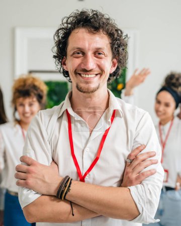 Photo for Portrait of adult man in front of group of people women female colleagues portrait caucasian male stand at work happy smile confident with curly modern hair wear white shirt copy space bright filter - Royalty Free Image