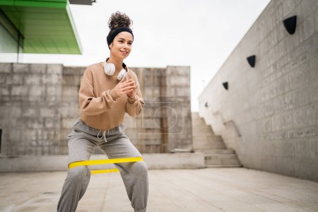 Téléchargez les photos : Une femme adulte caucasienne athlète entraînement féminin avec élastique élastique bandes de résistance en plein air dans la ville sur fond de béton étirement dans heureux brune santé et fitness concept copier l'espace - en image libre de droit