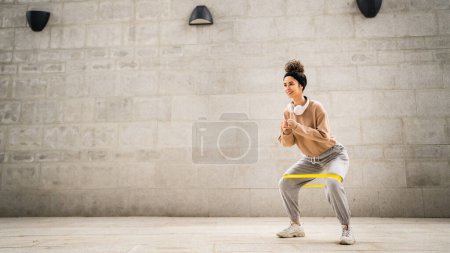 Photo for One woman adult caucasian female athlete training with elastic rubber resistance bands in outdoor in the city on concrete background stretching in happy brunette health and fitness concept copy space - Royalty Free Image