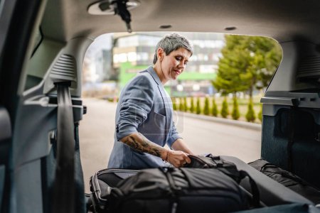 Photo for One senior beautiful woman travel concept female take luggage baggage suitcase and other stuff and belongings from the back of her car while moving or arrive to destination real people copy space - Royalty Free Image