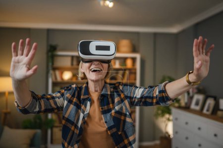 Foto de Una mujer madura senior caucásica hembra en casa disfrutar de realidad virtual VR auriculares - Imagen libre de derechos