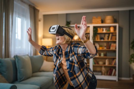 Téléchargez les photos : Une femme mature femme caucasienne âgée à la maison profiter de réalité virtuelle VR casque - en image libre de droit