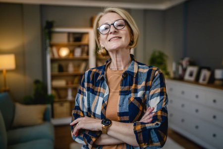 Photo for Portrait of one mature blonde caucasian woman with eyeglasses at home happy smile looking to the camera confident wear shirt copy space - Royalty Free Image