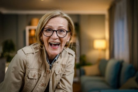 Foto de Retrato de una mujer caucásica rubia madura con anteojos en casa sonrisa feliz mirando a la cámara con confianza usar camisa copia espacio - Imagen libre de derechos